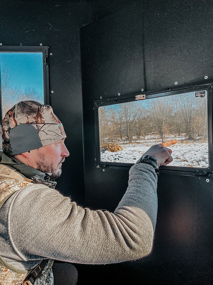 Man pointing out horizontal window in hunting blind